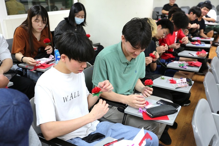 圖／活動中學生們體驗親手做康乃馨，一邊交流彼此家鄉過節的習俗，場面溫馨熱絡。