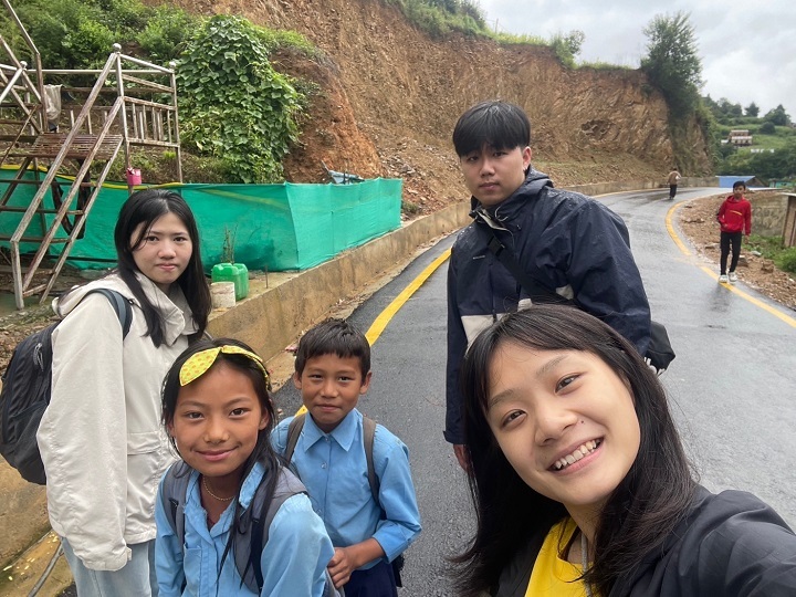 圖／餐旅系林士恩（後方男）與同樣來自台灣的志工一起護送學童返家，每逢下雨就要擔心土石滑落等危險。