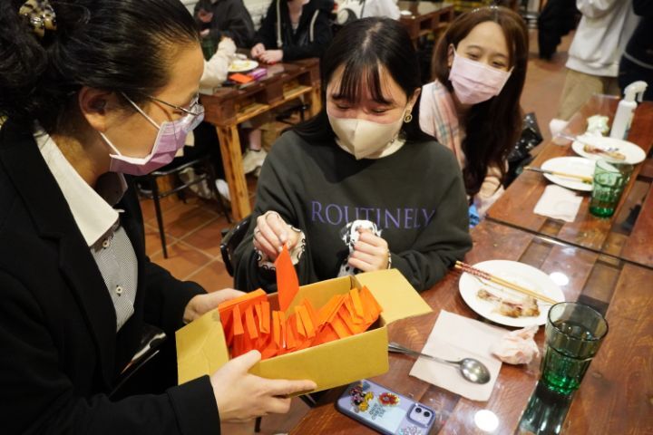 圖/簡曉花拿著裝有10元硬幣和幸運石的小紅包袋，依序向日籍生親自獻上祝福。