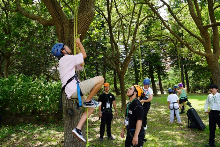 圖/新生與家長在美麗的校園中體驗攀樹活動。