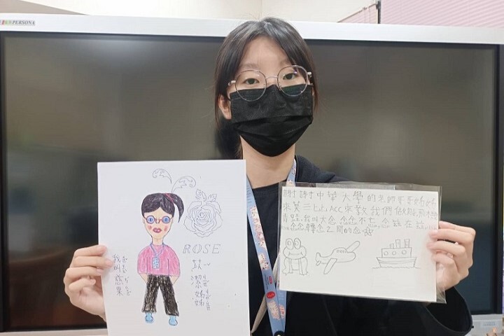 圖／國際志工團長林苡潔拿著孩子送給他的畫作和手寫信，相當感動！孩子們的畫作與志工服務照片皆可在中華大學行政大樓一樓欣賞。